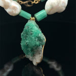 close up raw emerald pendant with natural pearls