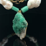 close up raw emerald pendant with natural pearls