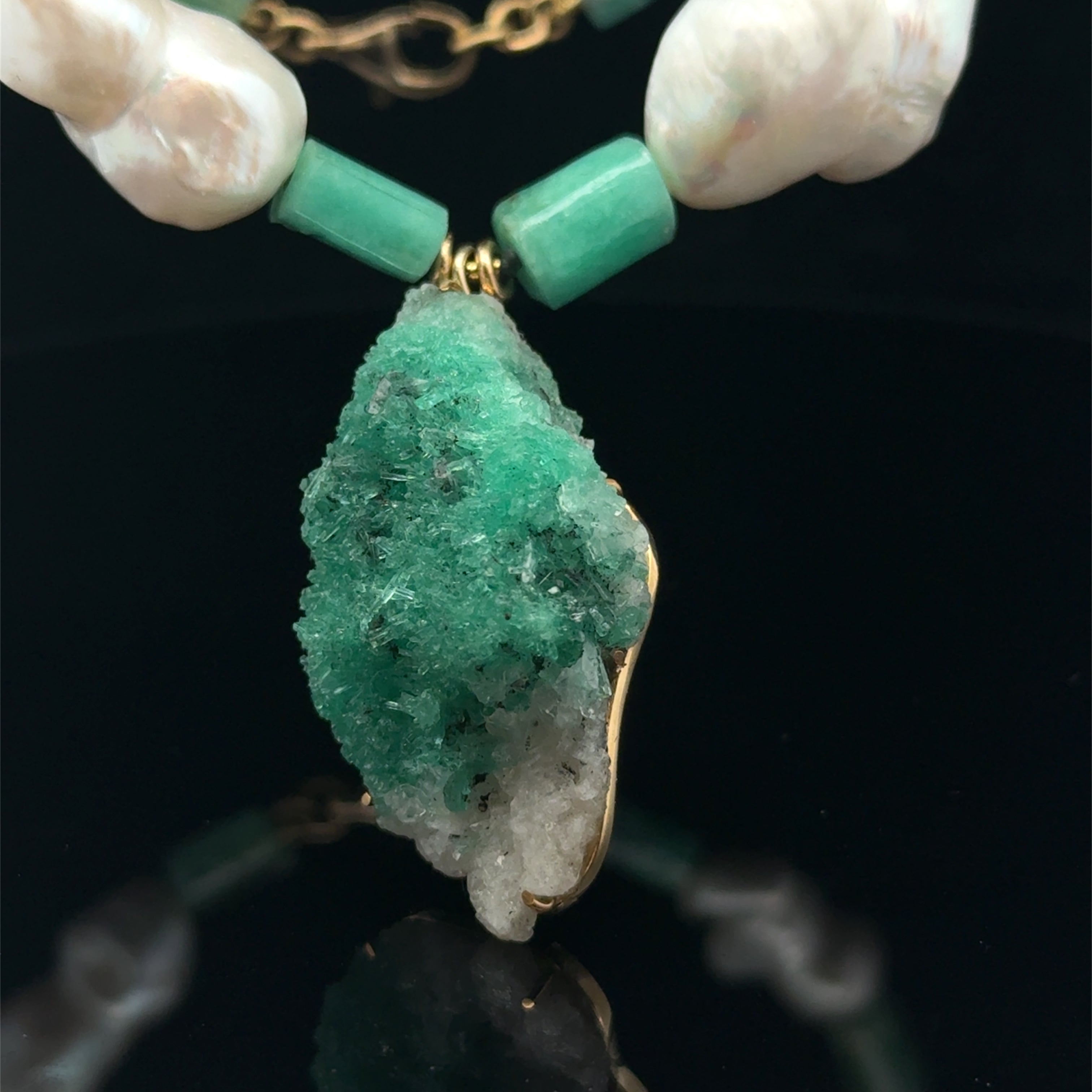 close up raw emerald pendant with natural pearls